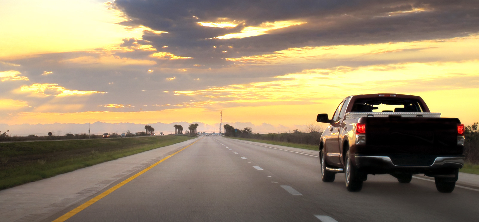 A truck on road in front of sunset