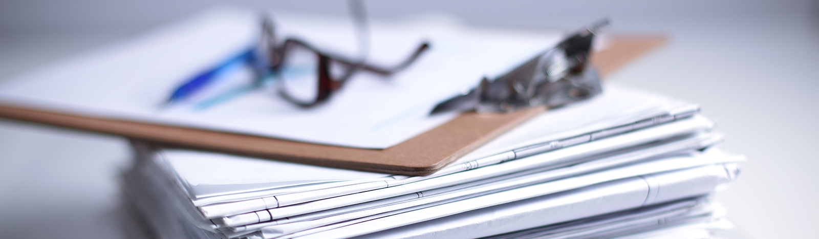 glasses and clipboard on a stack of papers